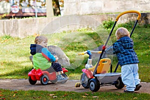 two little boys playing with cars and bikes outdoors. Happy children siblings in autumn park. Toddlers twins wears