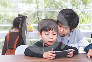 Two Little boys playing online game on mobile phone