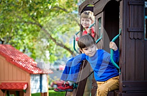 Two little boys playing together and having fun. Lifestyle family moment of siblings on playground. Kids friends play on tree