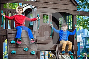 Two little boys playing together and having fun. Lifestyle family moment of siblings on playground. Kids friends play on tree