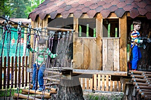 Two little boys playing together and having fun. Lifestyle family moment of siblings on playground. Kids friends play on tree