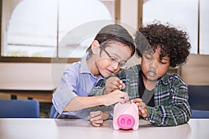 Two little boys putting money into piggy bank for future savings