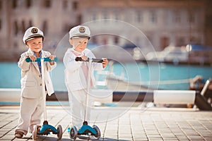 Two little boys riding on scooter bicycle in summer