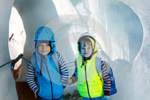 Two little boys with safety helmets and clothing with mountains landscape backgrounds. Kids hiking and discovering