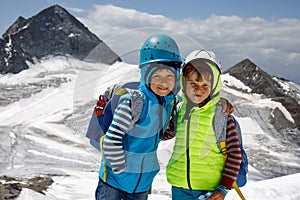 Two little boys with safety helmets and clothing with mountains landscape backgrounds. Kids hiking and discovering