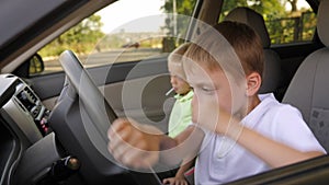 Two little boys are sitting in the car, they pretend to be adult drivers.