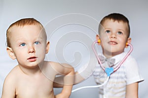 Two little boys using stethoscope. Children playing doctor and patient. Check the heartbeat.