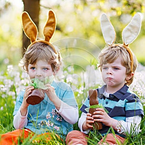 Two little boys wearing Easter bunny ears and eating chocolate