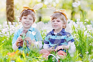 Two little boys wearing Easter bunny ears and eating chocolate