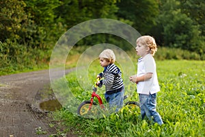 Two little brother boys playing near forest on summer evening. Cute siblings playing together.