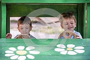 Two little brother toddlers playing with toy car in summer garden. Boys having fun and good time. In wooden at playground
