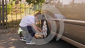Two little brothers fix the wheels in the car, the boy uses a torque wrench.