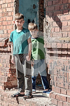 Two little brothers are orphans, living in an abandoned and abandoned house, children of war. Staged photo