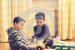 Two little brothers play in the playing room with an ambulance. toned