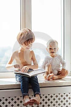 Two little brothers spending time together near window