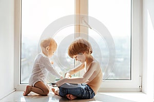 Two little brothers spending time together near window