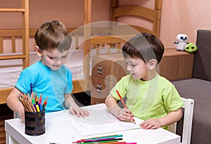 Two little caucasian friends playing with lots of colorful plastic blocks indoor. Active kid boys, siblings having fun building an