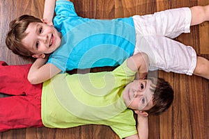 Two little caucasian friends playing with lots of colorful plastic blocks indoor. Active kid boys, siblings having fun building an