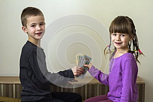 Two little children boy and girl playing with dollars money.