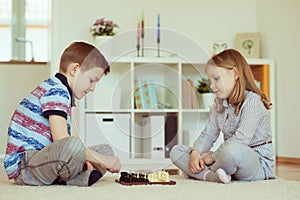 Two little children playing chess at home