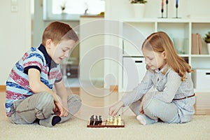 Two little children playing chess at home