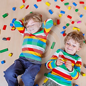 Two little children playing with colorful wooden blocks indoor