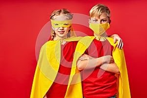 Two little children in superhero cloaks and masks