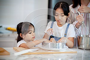 Two little cute Asian girls, learning how to make bread and bakery with a curious and happy smile face. She learns and plays