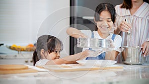 Two little cute Asian girls, learning how to make bread and bakery with a curious and happy smile face. She learns and plays