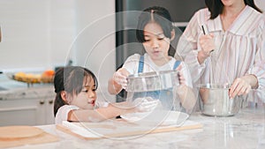 Two little cute Asian girls, learning how to make bread and bakery with a curious and happy smile face. She learns and plays