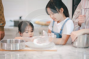 Two little cute Asian girls, learning how to make bread and bakery with a curious and happy smile face. She learns and plays