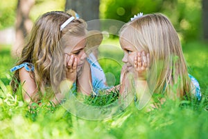 Two little cute girls lying on lawn