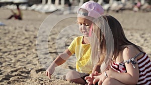 Two little cute girls playing with sand on the beach