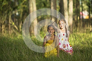 Two little cute girls posing in a pine forest. Game.