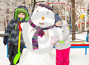 Two little fiends, kids making a snowman, playing and having fun with snow, outdoor on cold day. Active outdoors leisure with chil