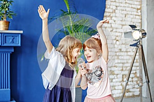 Two little funny children dance and sing a song in karaoke. The