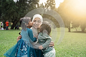 Two little girl kissing her mother