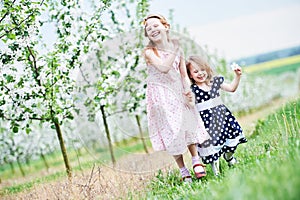 Two little girl run and having fun in spring garden