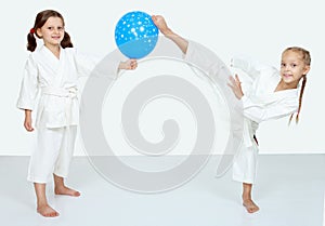 Two little girls with blue ball beat a karate kick leg