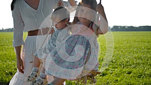 Two little girls in cute dresses swinging on a swing and happy dangling feet.