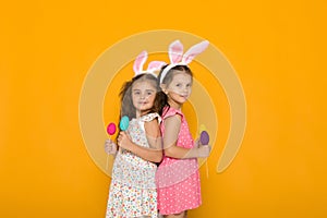 Little girls with Easter bunny ears holding colorful eggs