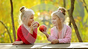 Two little girls eating a natural apples ,outdoors . Two little girls eating a natural apples in autumn Park. Healthily concept.