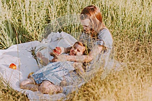 Two little girls enjoy summer in green field with wild grass. Big sister hugging younger one on picnic