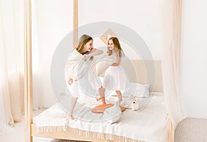 Two little girls fighting with pillows on the bed
