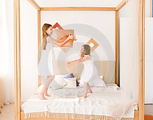 Two little girls fighting with pillows on the bed