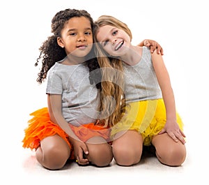 Two little girls-friends with different complexion sitting on the floor