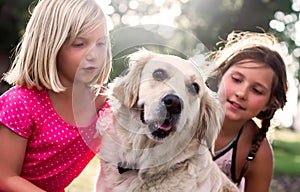 Two little girls with golden retriever dog