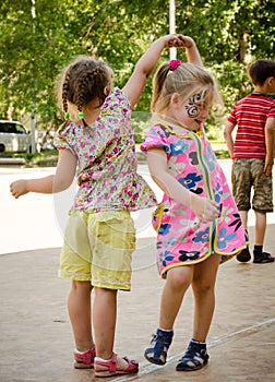 Two little girls holding hands dancing on a city holiday