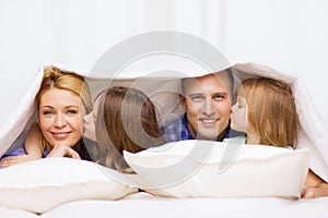 Two little girls kissing their parents on cheek