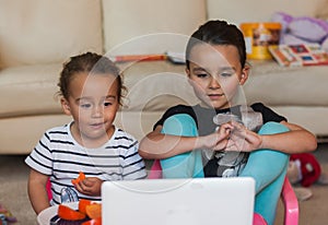 Two little girls with laptop at home